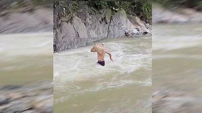 उत्तराखंड -कंधे में सामान रखकर उफ़नते गधेरे को पार करते हुए युवक का वीडियो वायरल, डीएम ने दिए जाँच के आदेश, ग्रामीण बोले 14 साल से पुल का इंतजार